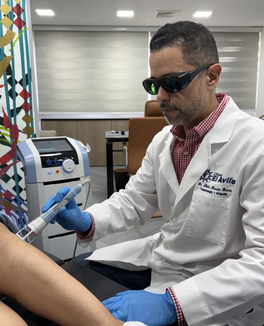 Dr. Pablo Briceño aplicando tratamiento de láser terapéutico en articulación de rodilla para manejo del dolor en Caracas.